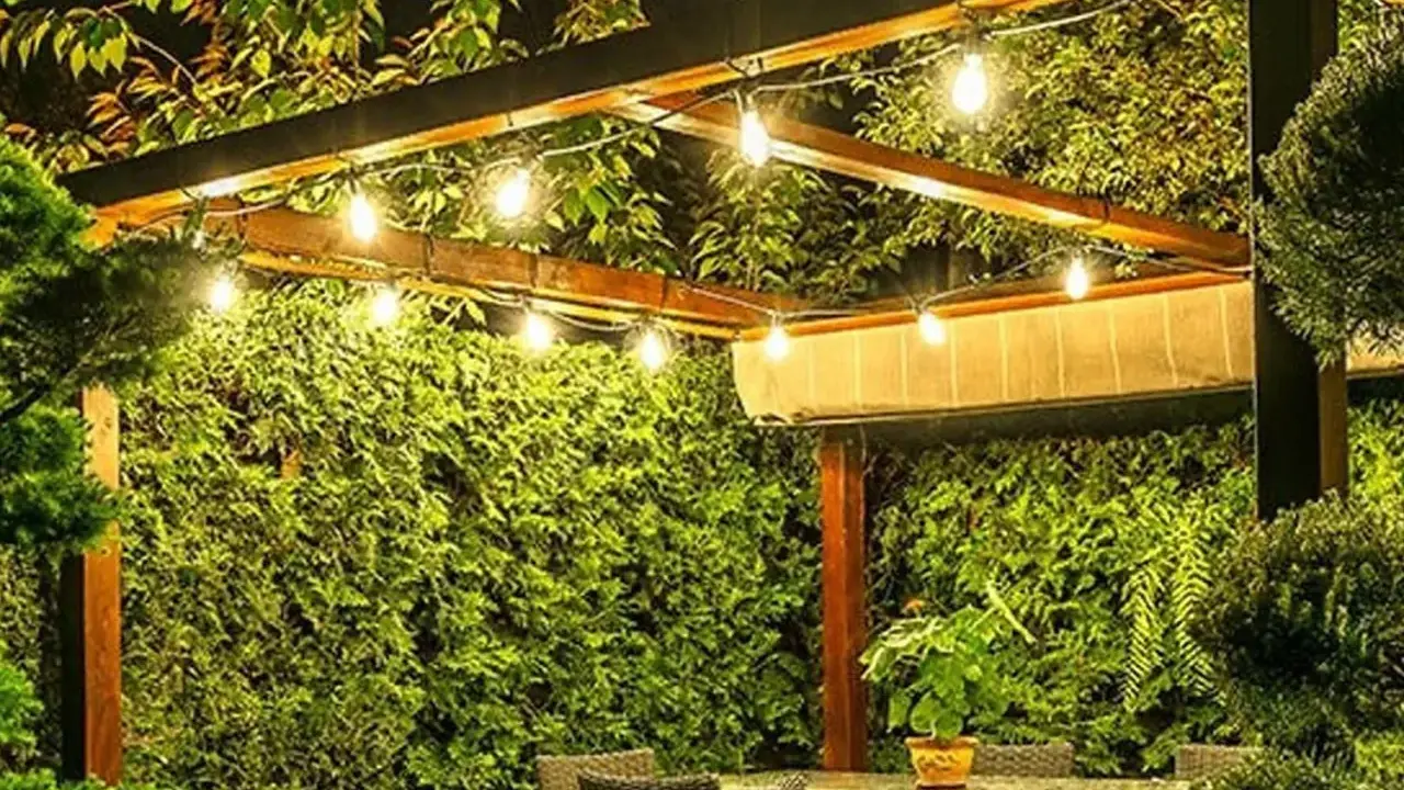 Guirlande lumineuse sous une pergola en bois, créant une ambiance chaleureuse. Le lux défini par ces ampoules éclaire un jardin luxuriant.