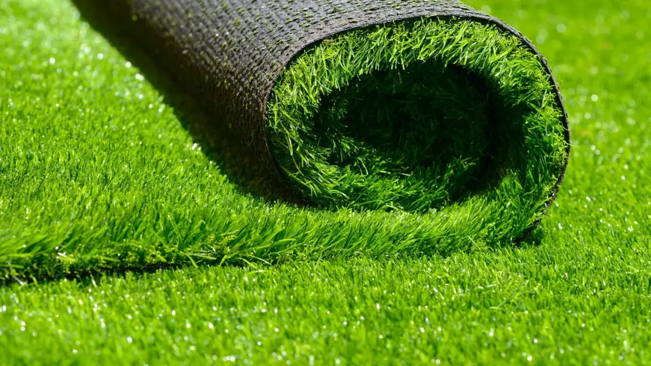 Rouleau de gazon synthétique vert vif, montrant le dessous noir et le dessus en fibres.