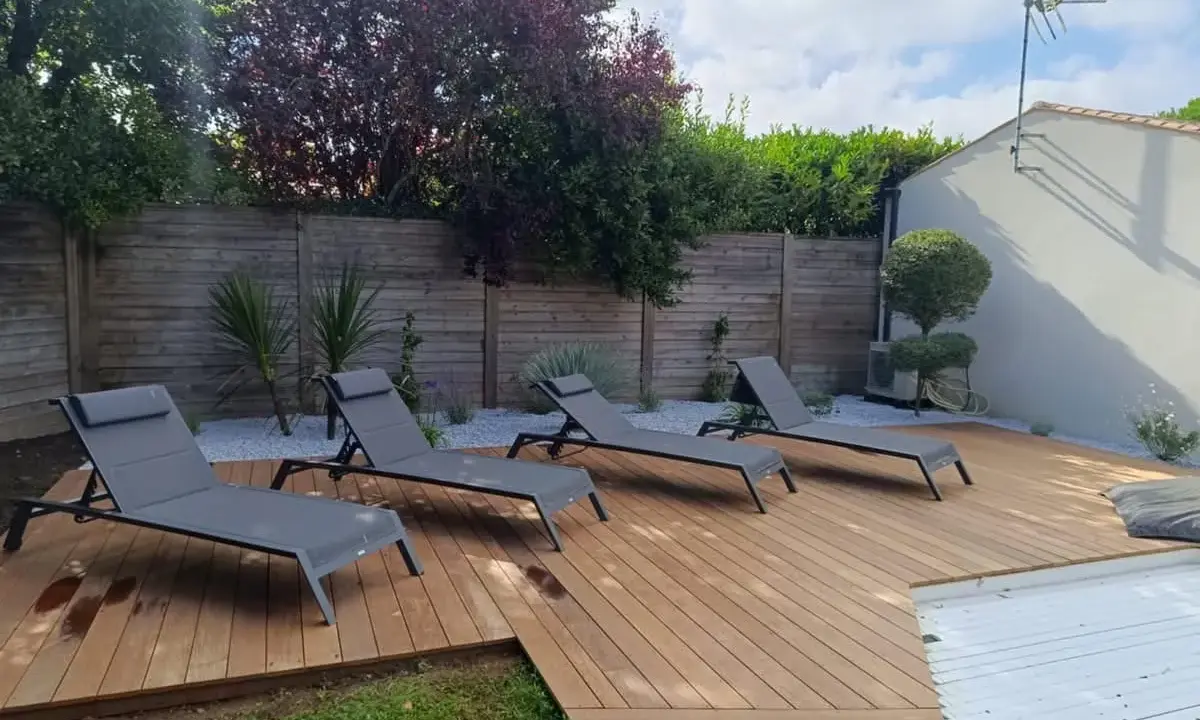 Terrasse en bois chaleureuse avec chaises longues, idéale pour se détendre. Le choix du quel bois pour terrasse est crucial pour un tel espace extérieur.