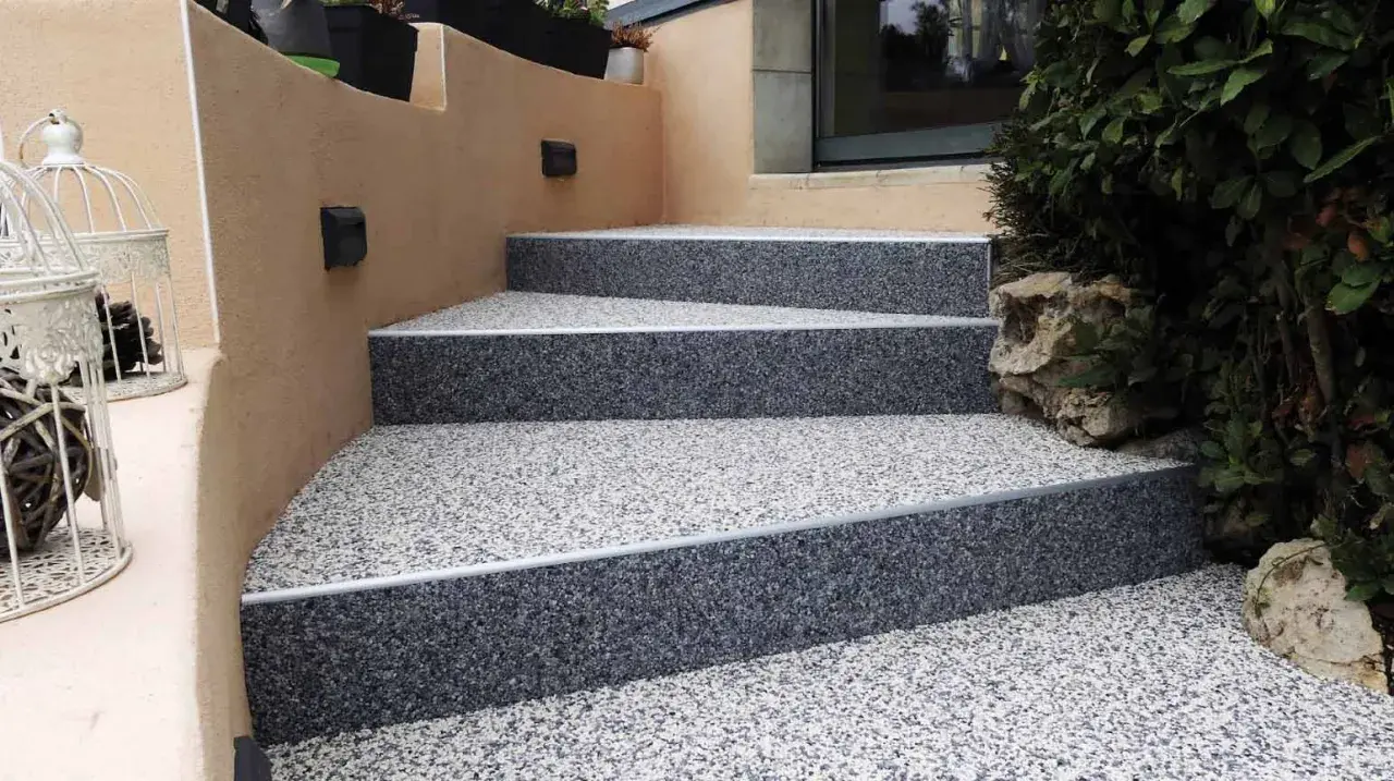 Escalier extérieur avec revêtement de sol en gravier coloré, un aménagement extérieur moderne et résistant.