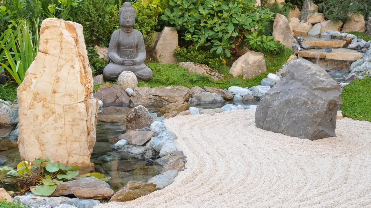 Jardin zen avec statue de Bouddha, cascade, étang et sable ratissé. Une allée de jardin facile à faire pour un coin de sérénité.