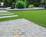 Une nouvelle terrasse a été refaite sur une ancienne, avec un mélange de pavés, de bois et de gazon synthétique.