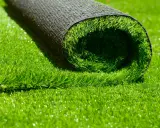Rouleau de gazon synthétique vert vif, montrant le dessous noir et le dessus en fibres.