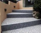 Escalier extérieur avec revêtement de sol en gravier coloré, un aménagement extérieur moderne et résistant.