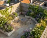 Idéal pour aménager un petit jardin de 10m2 : terrasse en pierre, banquette en bois, mobilier de jardin et massifs de lavande et graminées.