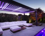 Pergola moderne avec éclairage LED violet, salon extérieur confortable, piscine illuminée. Une idée éclairage pergola pour une ambiance féerique.