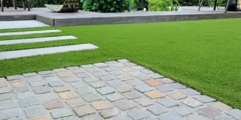 Une nouvelle terrasse a été refaite sur une ancienne, avec un mélange de pavés, de bois et de gazon synthétique.