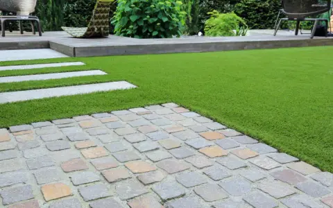 Une nouvelle terrasse a été refaite sur une ancienne, avec un mélange de pavés, de bois et de gazon synthétique.