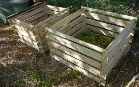 Deux composteurs maison en bois, l'un rempli de verdure, prêts à transformer les déchets de jardin en or noir.