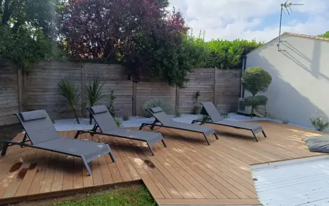 Terrasse en bois chaleureuse avec chaises longues, idéale pour se détendre. Le choix du quel bois pour terrasse est crucial pour un tel espace extérieur.