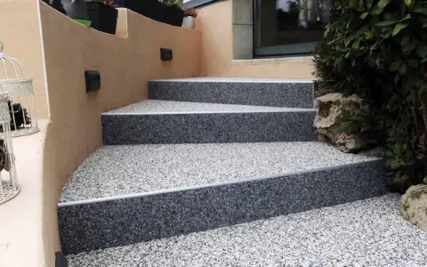 Escalier extérieur avec revêtement de sol en gravier coloré, un aménagement extérieur moderne et résistant.