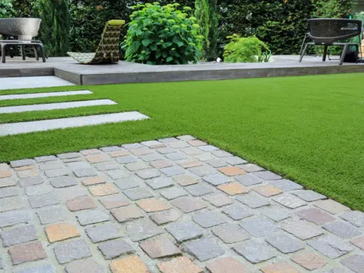 Une nouvelle terrasse a été refaite sur une ancienne, avec un mélange de pavés, de bois et de gazon synthétique.
