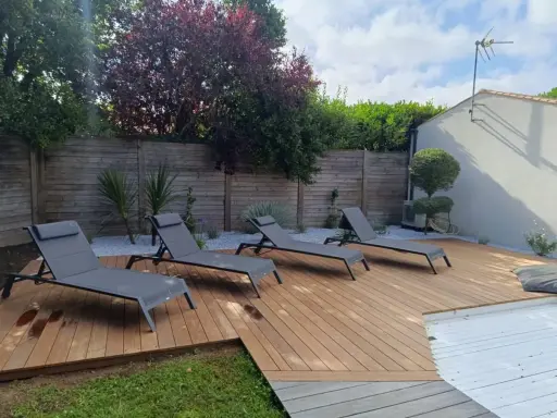 Terrasse en bois chaleureuse avec chaises longues, idéale pour se détendre. Le choix du quel bois pour terrasse est crucial pour un tel espace extérieur.