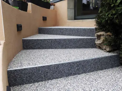 Escalier extérieur avec revêtement de sol en gravier coloré, un aménagement extérieur moderne et résistant.