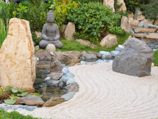Jardin zen avec statue de Bouddha, cascade, étang et sable ratissé. Une allée de jardin facile à faire pour un coin de sérénité.