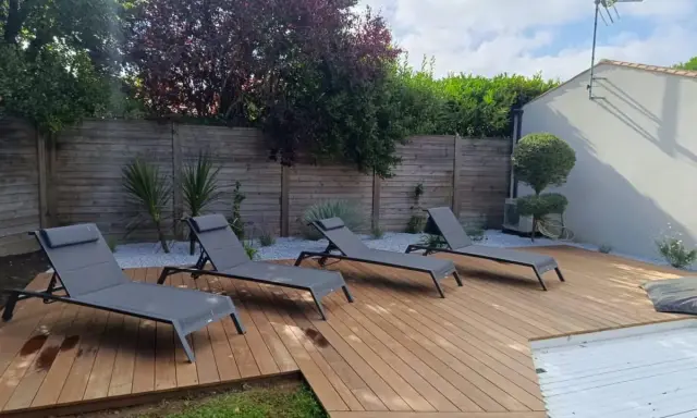 Terrasse en bois chaleureuse avec chaises longues, idéale pour se détendre. Le choix du quel bois pour terrasse est crucial pour un tel espace extérieur.