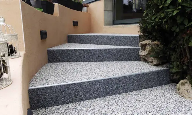 Escalier extérieur avec revêtement de sol en gravier coloré, un aménagement extérieur moderne et résistant.