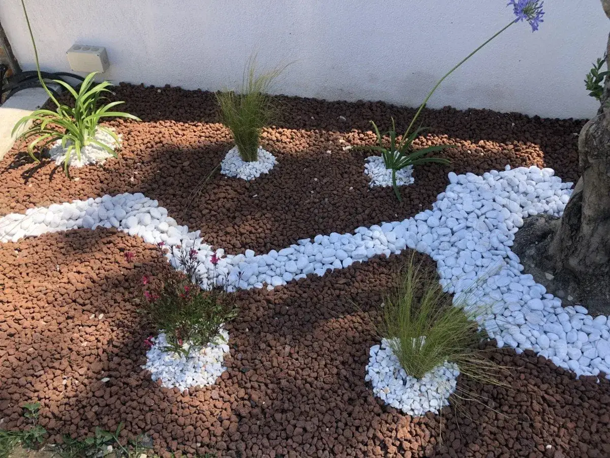 Un jardin paysager avec des pierres blanches et de la pouzzolane rouge. Ces mat&eacute;riaux sont parfaits pour savoir que mettre au sol pour &eacute;viter les mauvaises herbes.